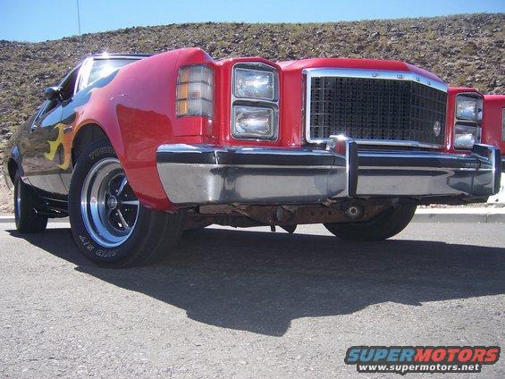 Red pickup truck with flames, chrome bumper, and grille. Front view