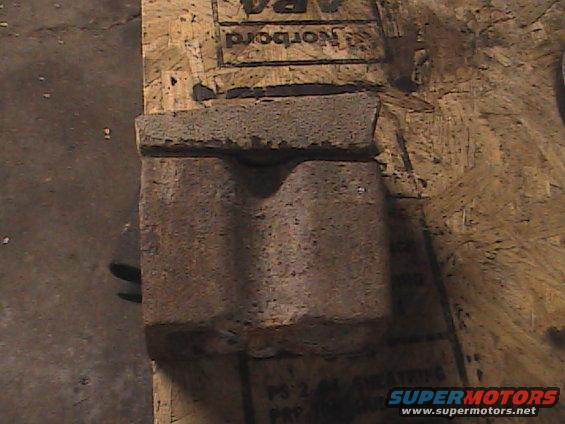 Concrete block with a curved indentation on plywood, Supermotors.net logo visible
