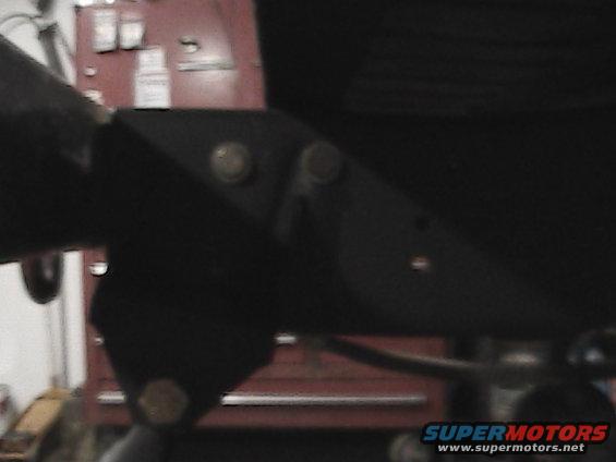 Black metal bracket with bolts, part of a vehicle's suspension