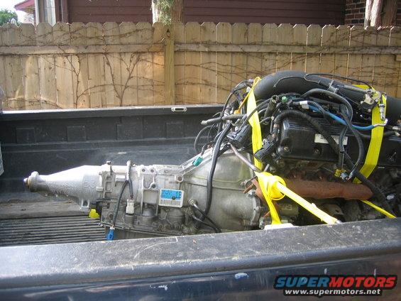 Engine and transmission secured with yellow straps in the bed of a pickup truck