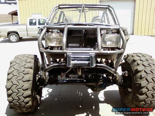 Off-road vehicle with custom roll cage, large tires, and winch, viewed from the front