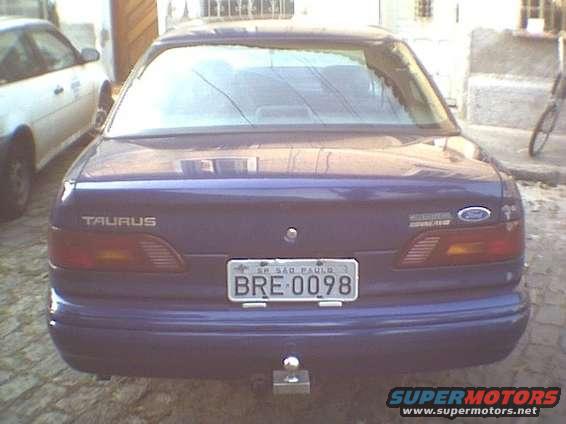 Rear of a purple Ford Taurus with a trailer hitch. Another white car is parked to the left