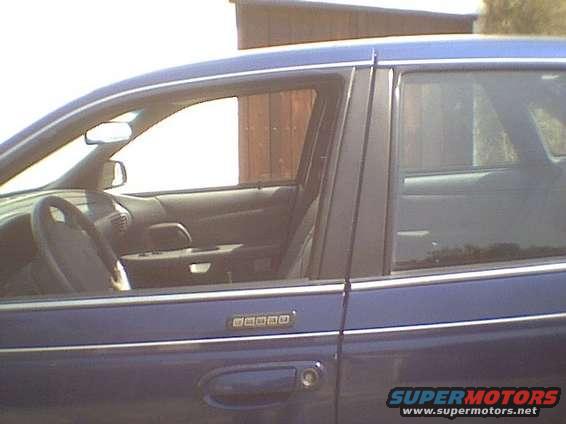 Blue sedan side profile showing interior door panel, steering wheel, and a keypad on the door