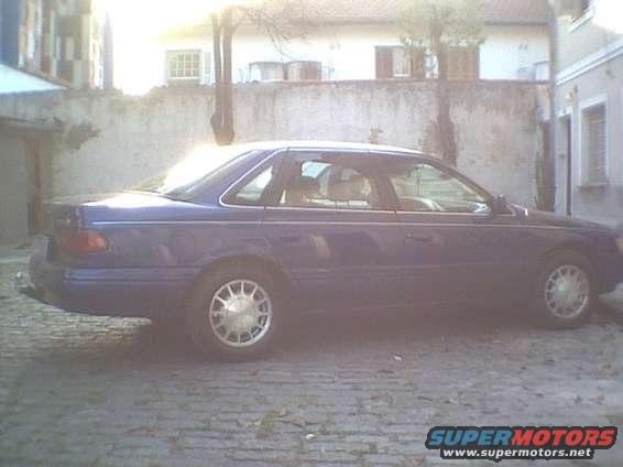 1995 Ford Taurus sedan, side view. Blue paint, tan interior visible