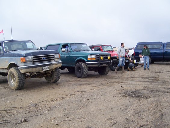 1996 Ford Bronco and other off-road vehicles parked on dirt with people standing around