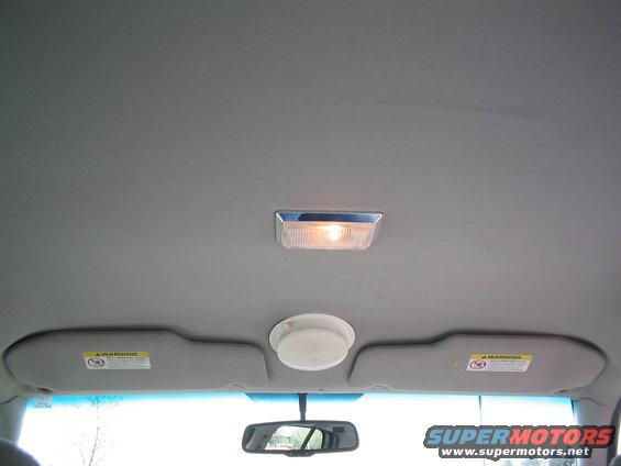 Interior shot of a car's ceiling, showing a light fixture, two sun visors, and a rearview mirror