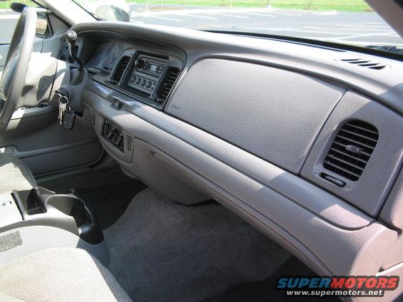 Gray dashboard of a 2001 Ford Crown Victoria, showing the steering wheel, radio, and air vents