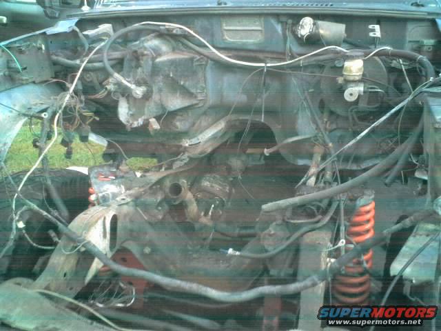 Engine bay with exposed wiring and rusty components, showing a red coil spring
