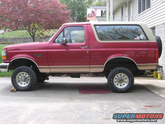 Red Ford Bronco with tan trim, side view, lifted suspension, spare tire on rear door