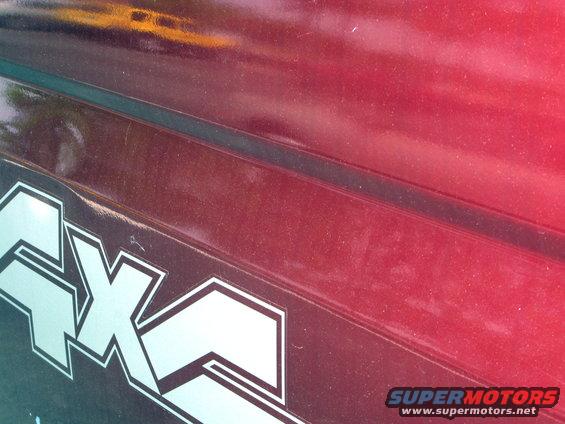 Close-up of a silver 4x4 decal on a red vehicle's body panel