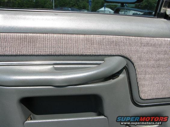 Close-up of a gray truck door panel with a plaid fabric insert and a gray handle