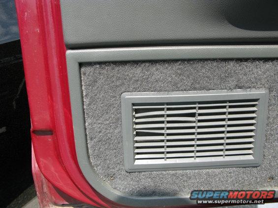 Red car door and gray interior panel with a vent. Watermark "SUPERMOTORS.NET" visible