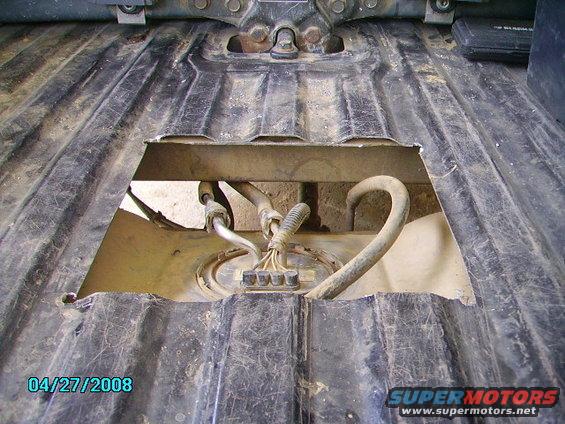 View of a vehicle's fuel pump assembly accessed through an opening in the undercarriage