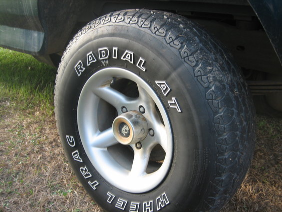 Close-up of a vehicle's wheel and tire. The tire has 'RADIAL AT WHEEL TRAC' written on it