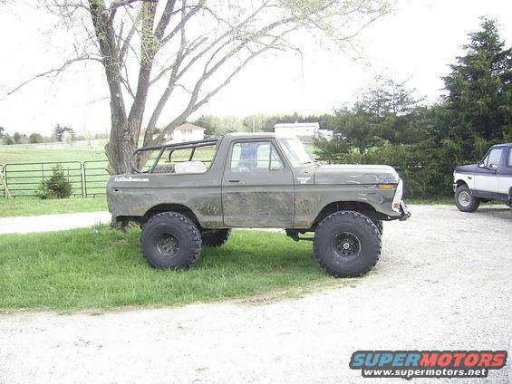 Olive green 1978 Ford Bronco with flame decals, roll cage, and large tires