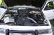 1996 Ford Crown Victoria - The engine bay of a white 1996 Ford Crown Victoria is visible with the hood open, revealing the engine and an Interstate battery.