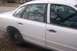 1996 Ford Crown Victoria - Side view of a white sedan with chrome trim and door handles, reflecting bare tree branches.