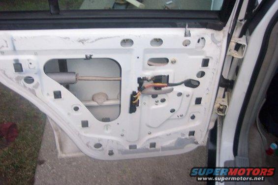 Interior of a white car door panel with exposed mechanics and wiring
