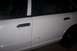 1996 Ford Crown Victoria - Close-up of a white sedan's side, showing door handles, a dent, and the rear tire.