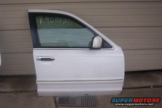 White car door with chrome handle and trim, against a beige wall