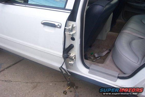 White 1996 Ford Crown Victoria door interior with exposed wiring and gray leather seats