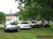 1996 Ford Crown Victoria - Four sedans are parked on a grassy lawn in front of a house and trees.