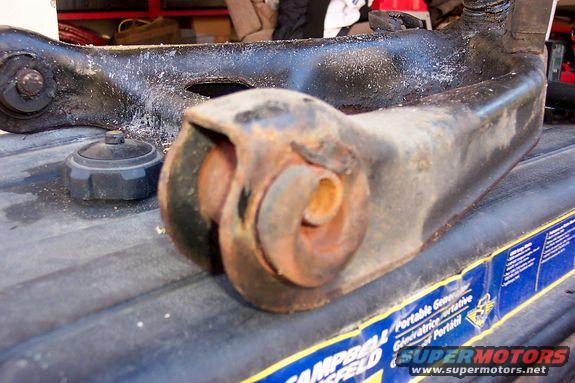 rusted car suspension control arm and a black cap sitting on a ribbed surface with a generator label