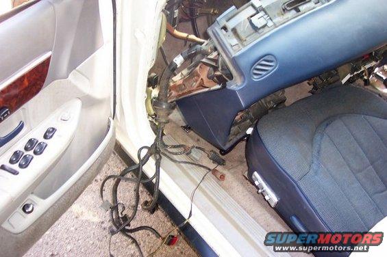 Car interior disassembled, showing door panel, seat, and dashboard components with exposed wiring
