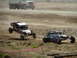 2008 Ford Bronco - Off-road buggies compete on a dirt track, with one vehicle jumping over a mound.