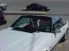 1989 Ford Mustang - A white 1989 Ford Mustang convertible is parked, with a dog visible in the driver's seat.