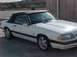 1989 Ford Mustang - A white convertible with a black top and red side stripe is viewed from the front three-quarter angle.