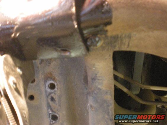 Close-up of rusty vehicle frame with visible welds and brake lines