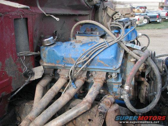 Blue engine with rusty exhaust manifolds, viewed from the front