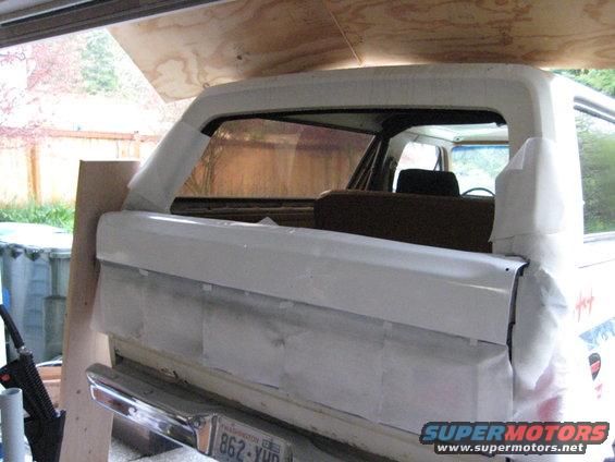 Rear of a white Ford Bronco, taped up for paint. Washington license plate visible