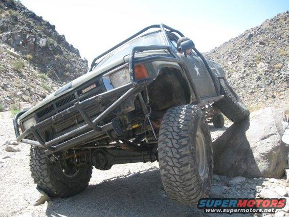 Modified Toyota 4Runner with roll cage and brush guard climbing over rocks