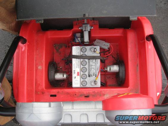 Open red housing showing a GEL battery, two electric motors, and wiring. Supermotors.net logo visible