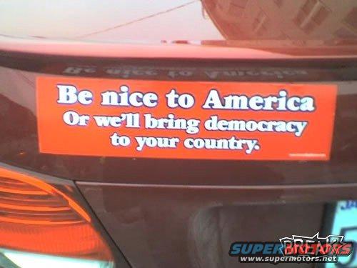 Brown car rear with an orange bumper sticker reading "Be nice to America Or we'll bring democracy to your country."