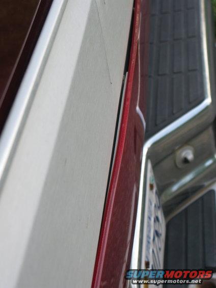 Close-up of a dark red pickup truck's rear corner with a license plate.