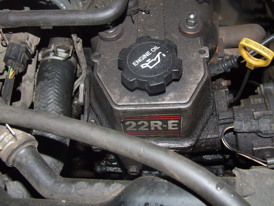 Engine bay with some hoses and a cap that says 'OIL'