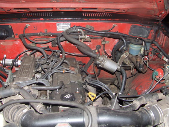 Engine bay with red paint and complex wiring. Some metal components are visible