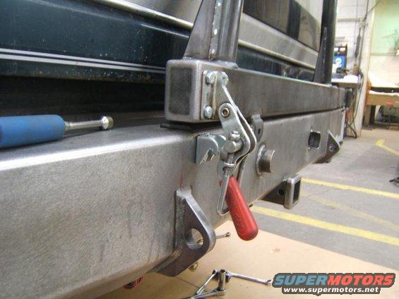 Close-up of a metal rear bumper with red tow hook attachment