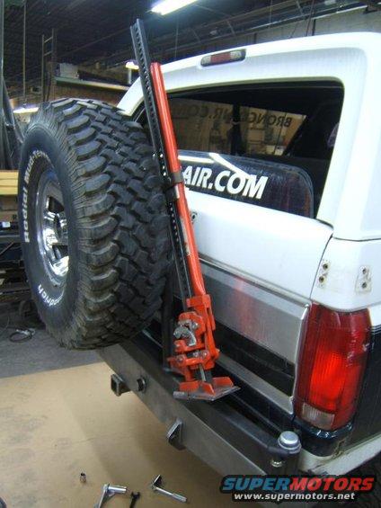 1993 Ford Bronco rear bumper with spare tire mounted and a red Hi-Lift jack attached