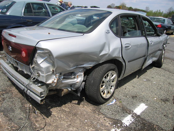 Silver sedan with rear bumper removed and extensive damage to rear quarter panel and doors