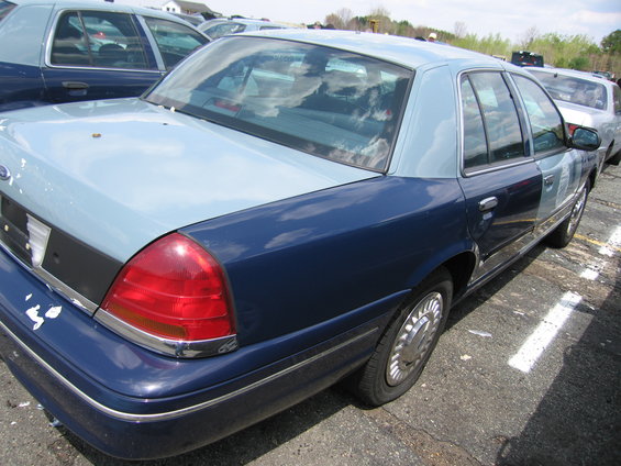 Two-tone blue Ford Crown Victoria, rear quarter panel, taillight, and wheel visible