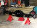 1996 Ford Bronco - A black rear axle assembly is supported by red jack stands in a garage setting.