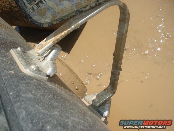 Close-up of a metal bracket and tire in muddy water