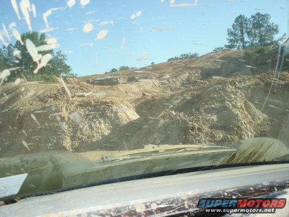 View from inside a vehicle looking out at a muddy, hilly construction area