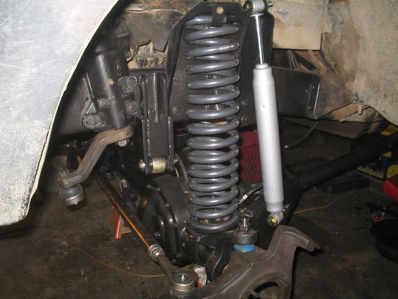 close-up of vehicle's front suspension with large coil spring and shock absorber