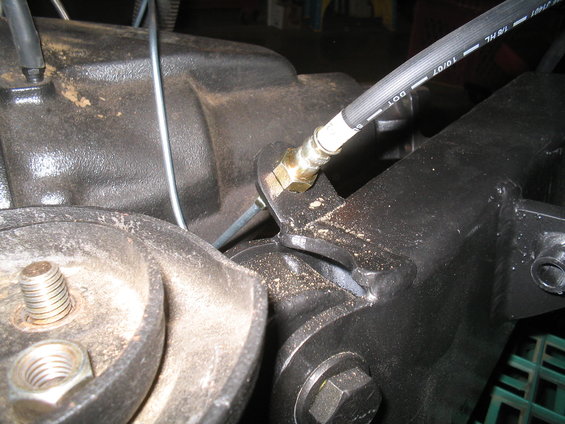 Close-up of a black brake hose connected to a metal bracket on a vehicle's suspension