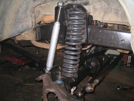 Front suspension with coil spring, shock absorber, and steering linkage